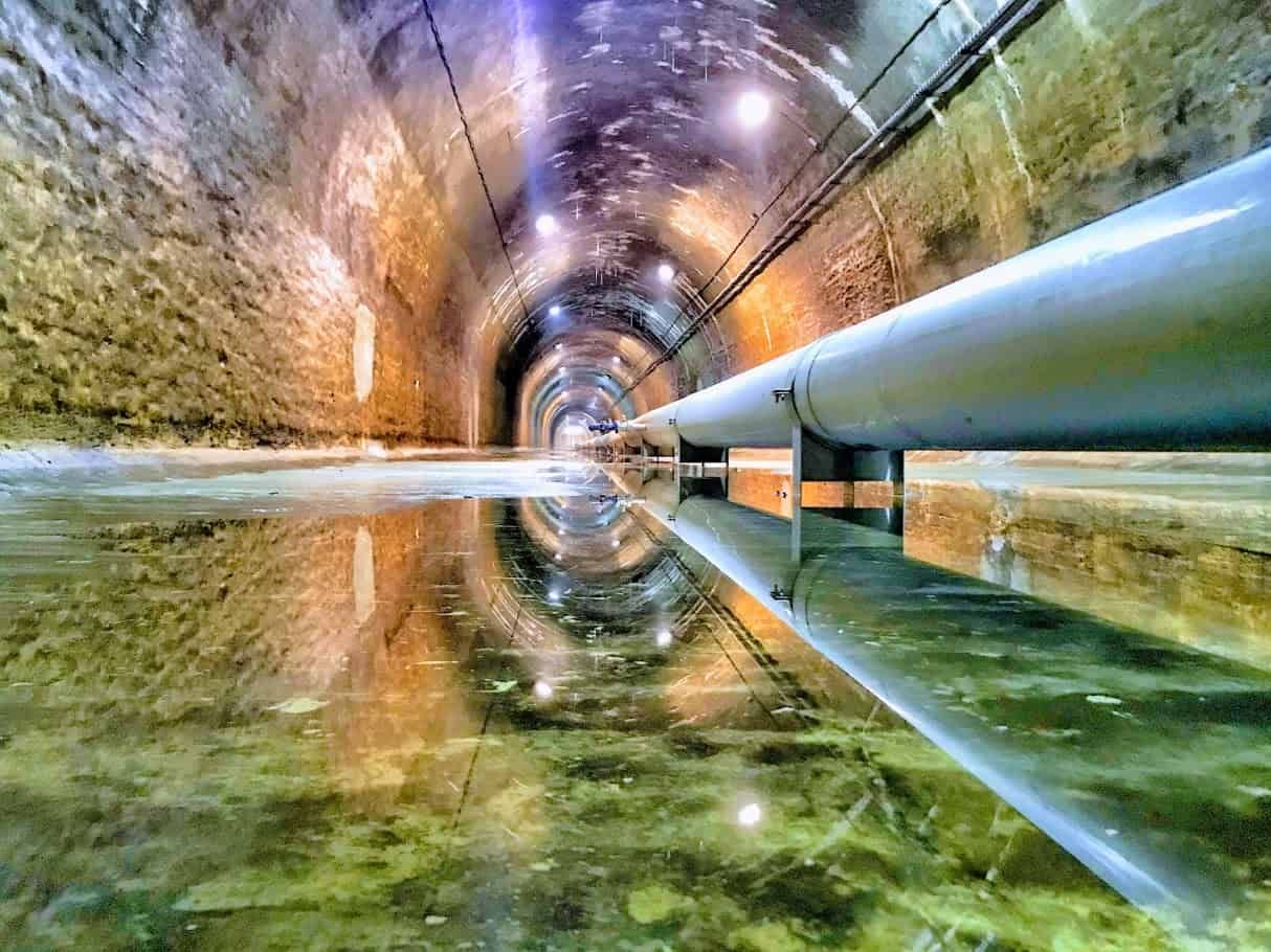 Técnico de Fhimasa con un equipo de detección de fugas o un caudalímetro en una arqueta, formato panorámico.