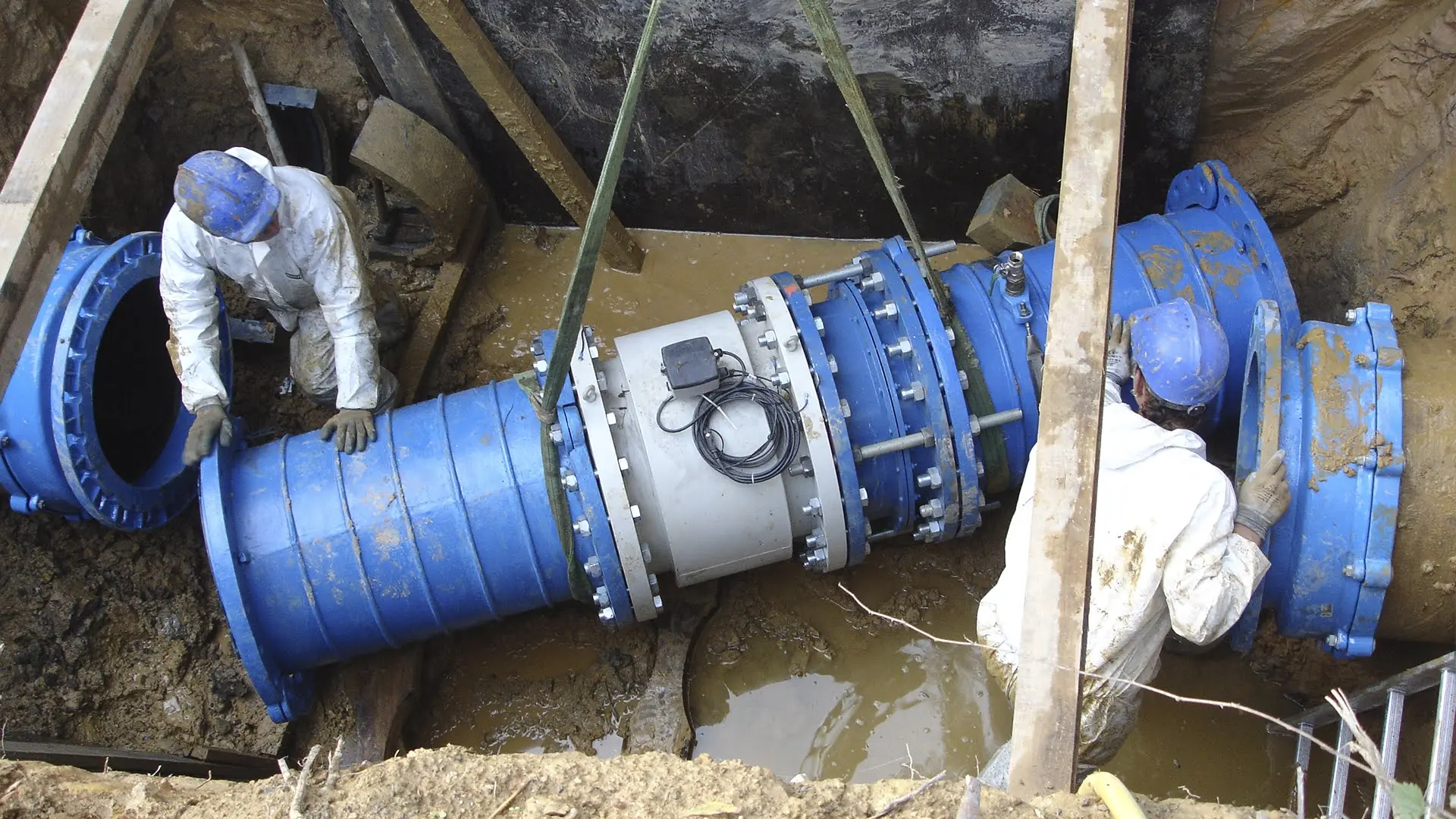 Obra de referencia a sangre: cuadrilla trabajando en una canalización urbana, formato panorámico.
